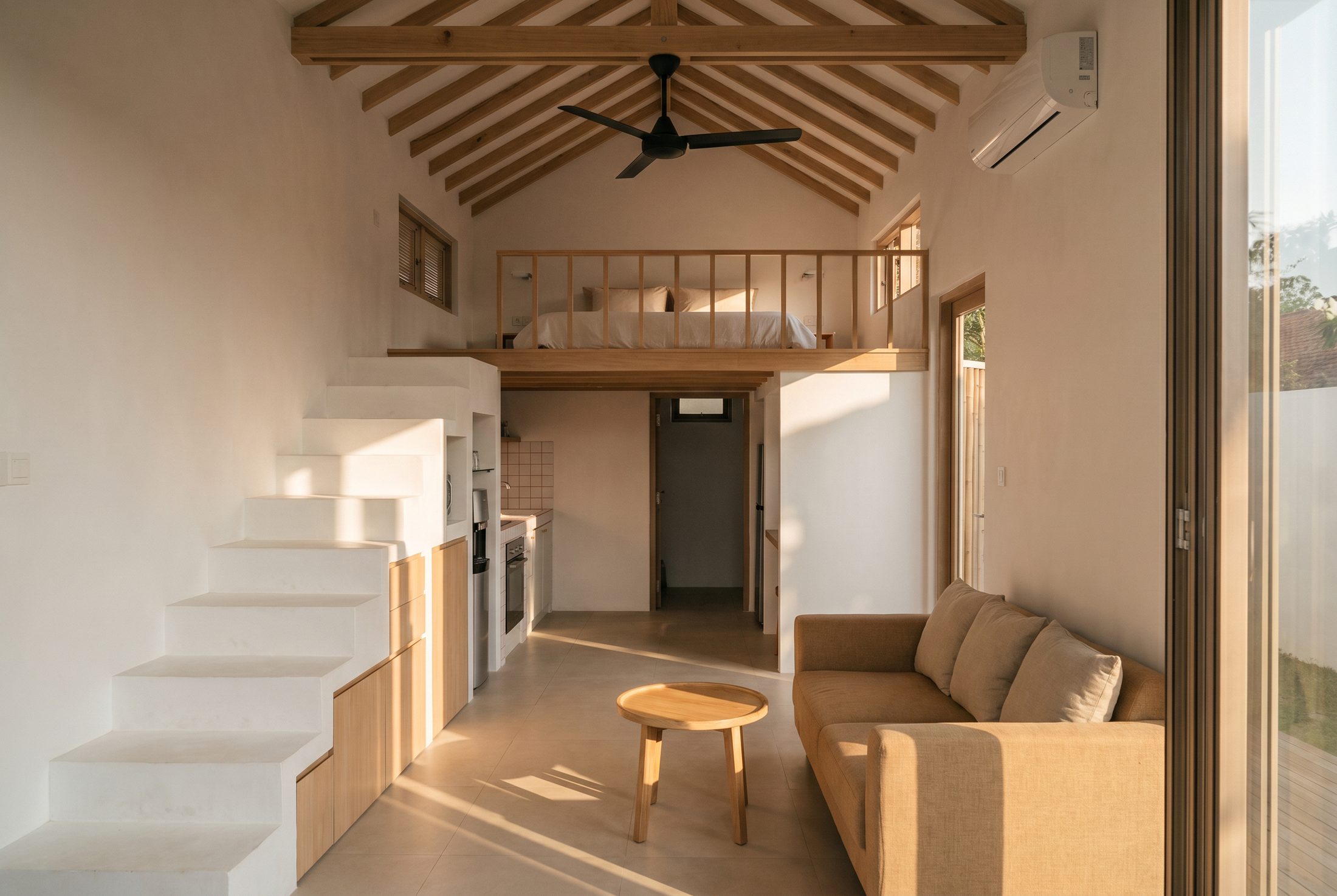 Warm, wood-beamed living room with loft above